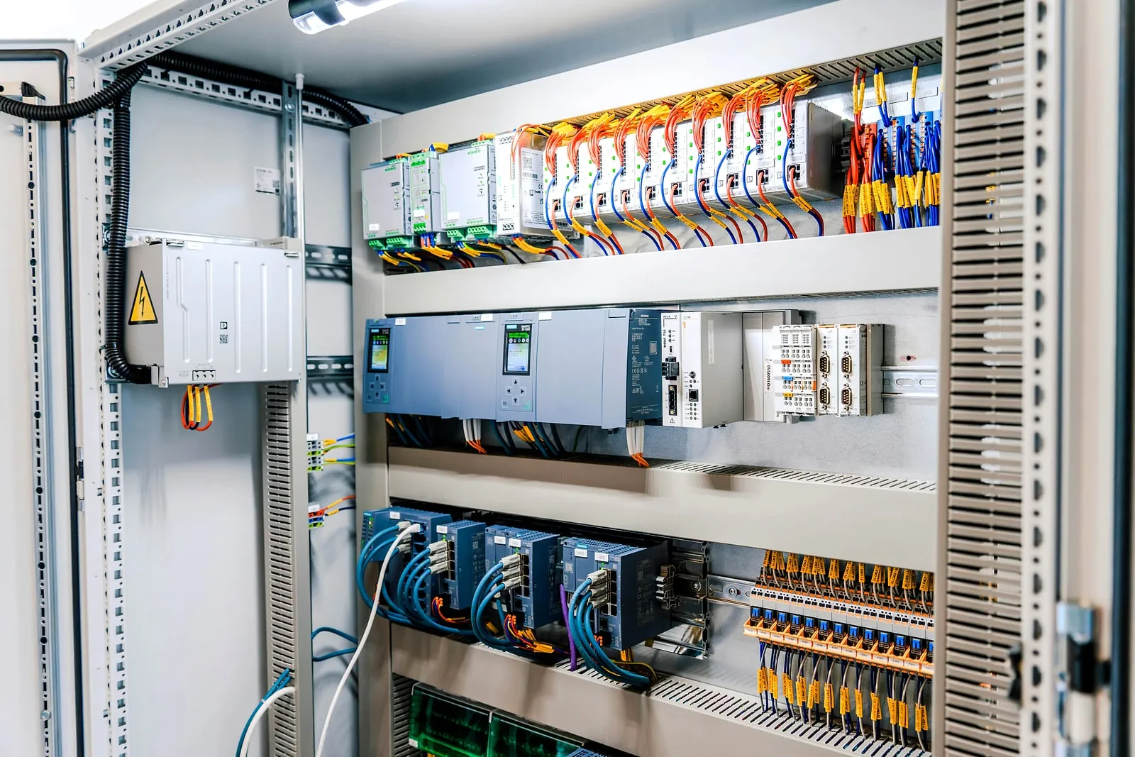 Open control cabinet with PLC modules, power supplies, network switches and terminal blocks